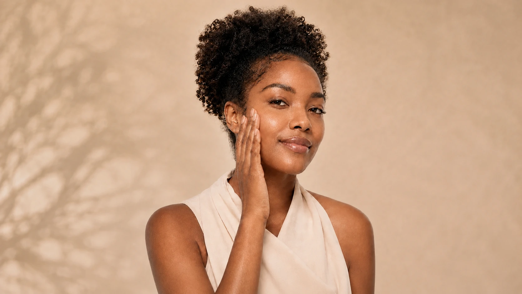 Mulher negra aplicando protetor solar no rosto, espalhando o produto de forma uniforme sobre a pele.